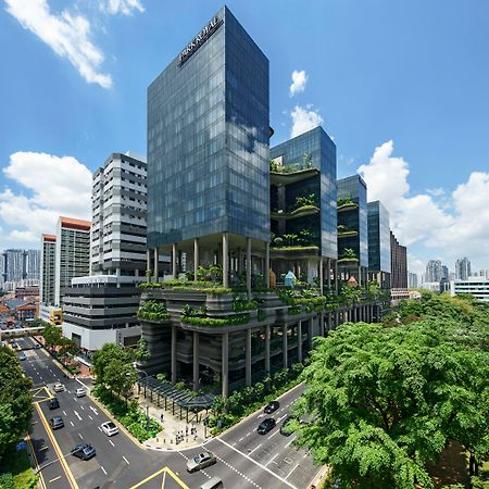 新加坡皮克林宾乐雅臻选酒店 外观 照片 The photo shows a modern urban architecture scene featuring several sleek glass buildings. These structures are complemented by greenery, with plants and trees integrated into their design, creating a lush environment. The scene includes a busy road 