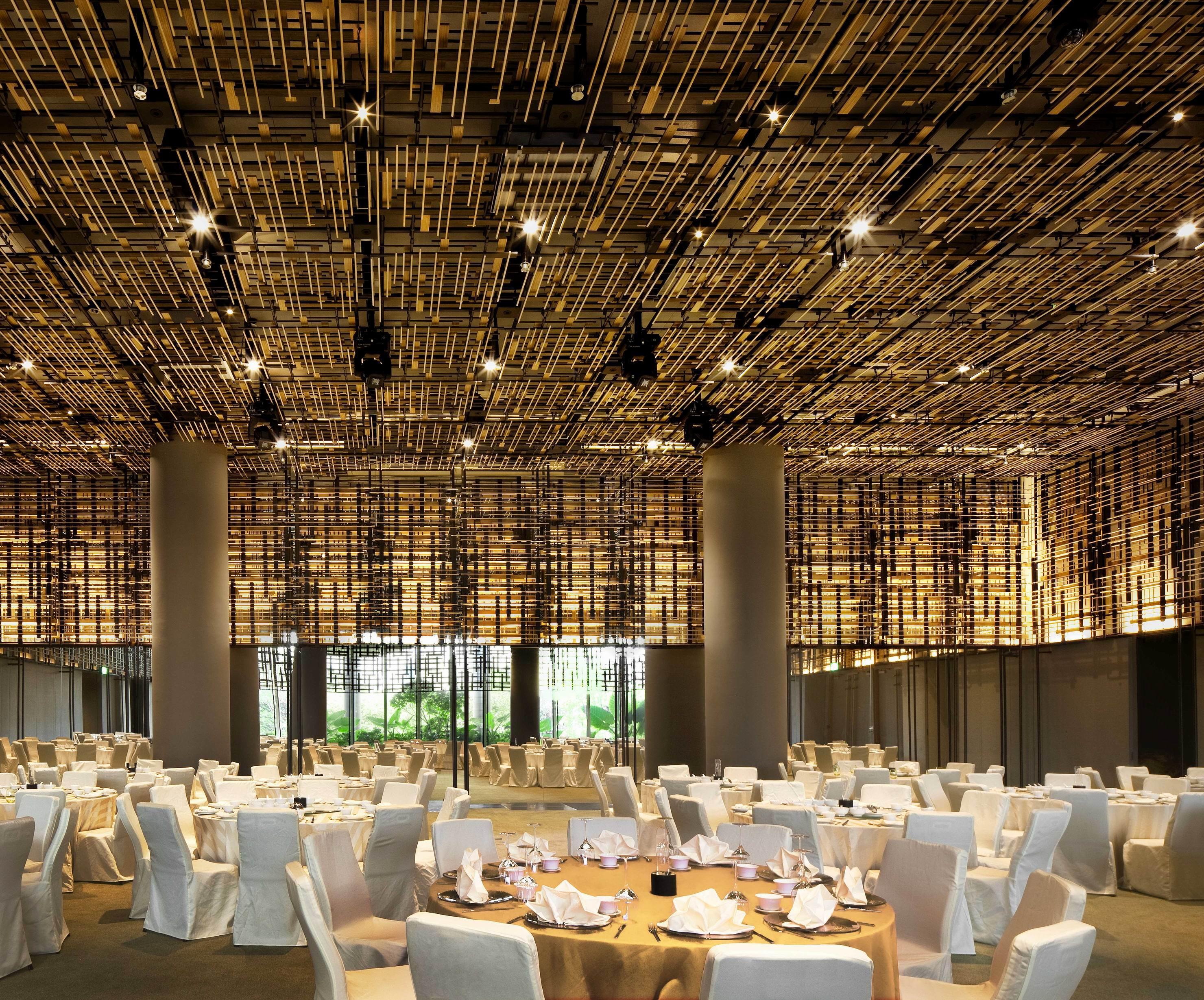 新加坡皮克林宾乐雅臻选酒店 外观 照片 The photo shows a spacious dining area with a modern and elegant design. The ceiling features a unique installation of bamboo or wooden elements that creates a textured appearance. The room is filled with round tables, each set with white tablecloths