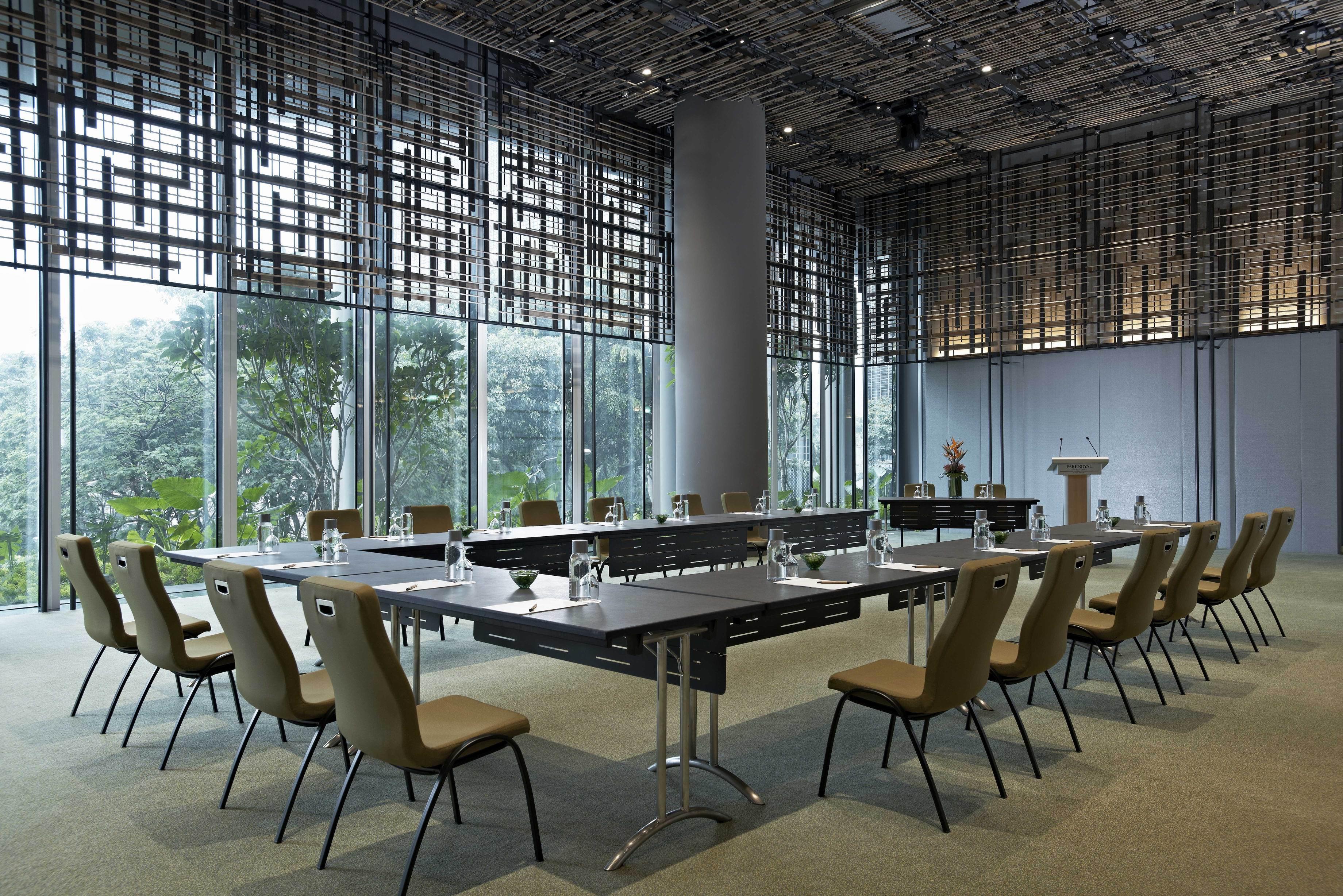 新加坡皮克林宾乐雅臻选酒店 外观 照片 The image shows a modern conference room. It features a long, rectangular table surrounded by several chairs. The table is equipped with glass water bottles and glasses. Large windows provide natural light and offer a view of greenery outside. The ro