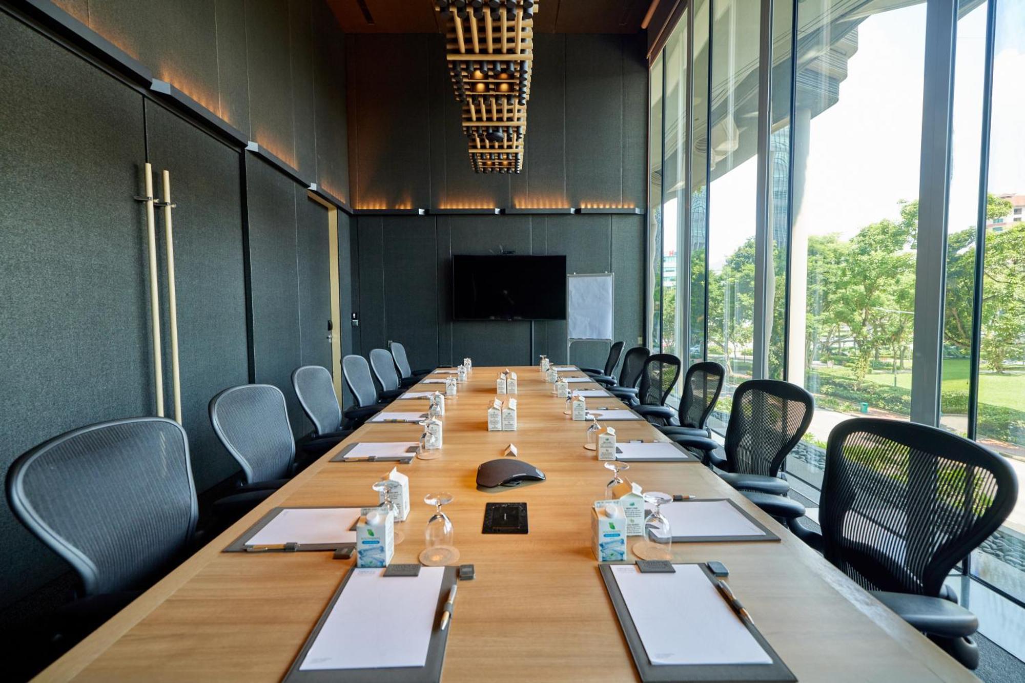 新加坡皮克林宾乐雅臻选酒店 外观 照片 The photo shows a modern conference room designed for meetings. It features a long wooden table surrounded by ergonomic chairs. On the table, there are several pieces of stationery, including notepads and pens, as well as small water bottles. A centr