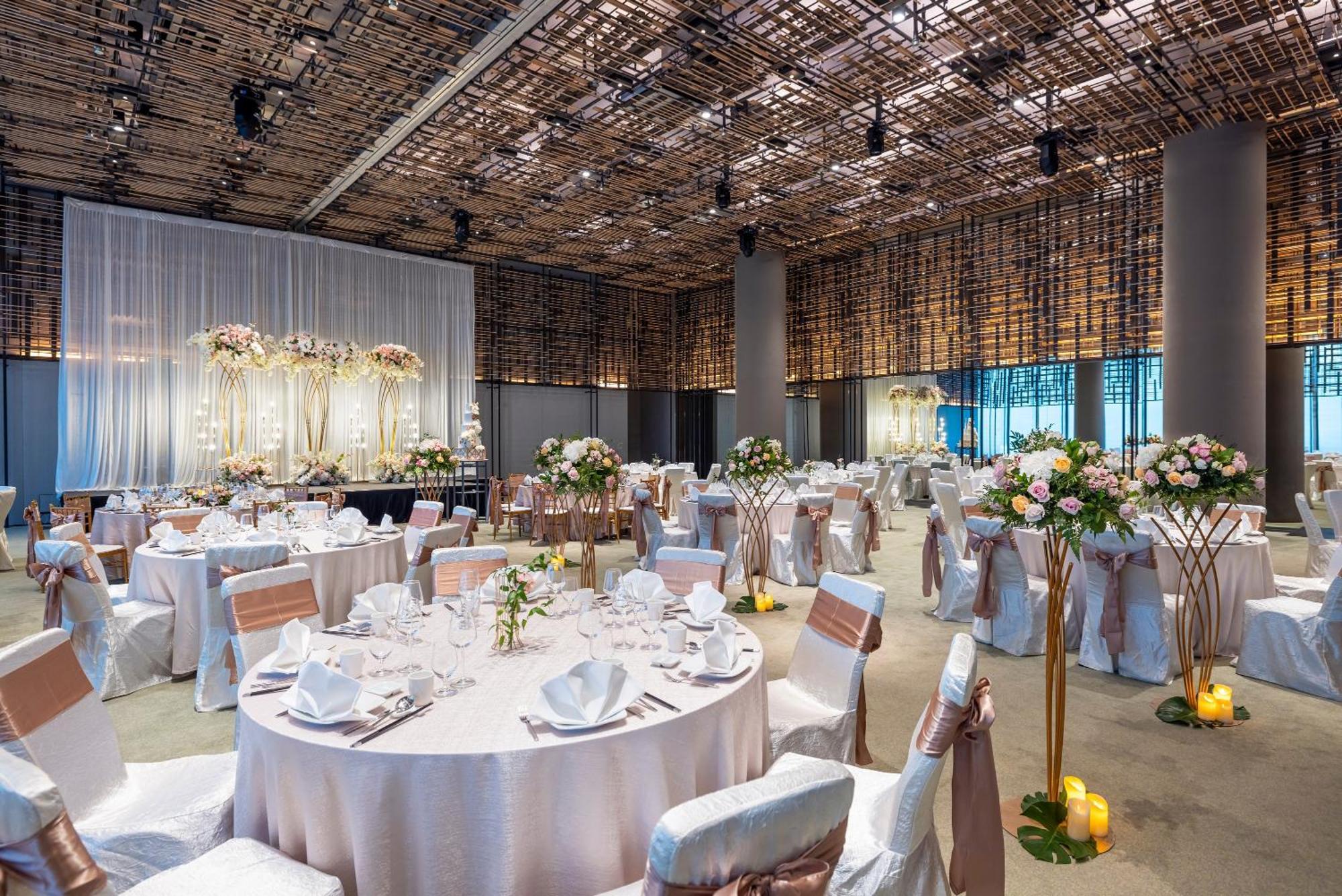 新加坡皮克林宾乐雅臻选酒店 外观 照片 The photo shows an elegantly decorated banquet hall set up for a wedding or formal event. The room features multiple round tables, each draped in white tablecloths and adorned with floral centerpieces. The chairs are covered with white fabric and tie