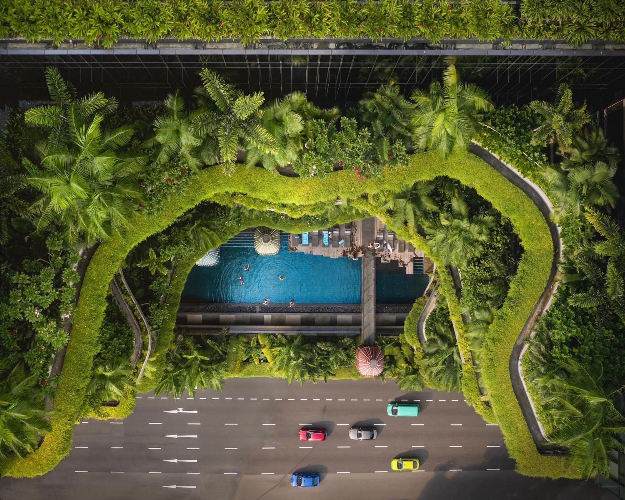 新加坡皮克林宾乐雅臻选酒店 外观 照片 The photo shows an aerial view of a green, lush landscape featuring a swimming pool surrounded by palm trees and other vegetation. The pool area is integrated into a modern architectural design, likely part of a hotel or resort, with paths and seatin