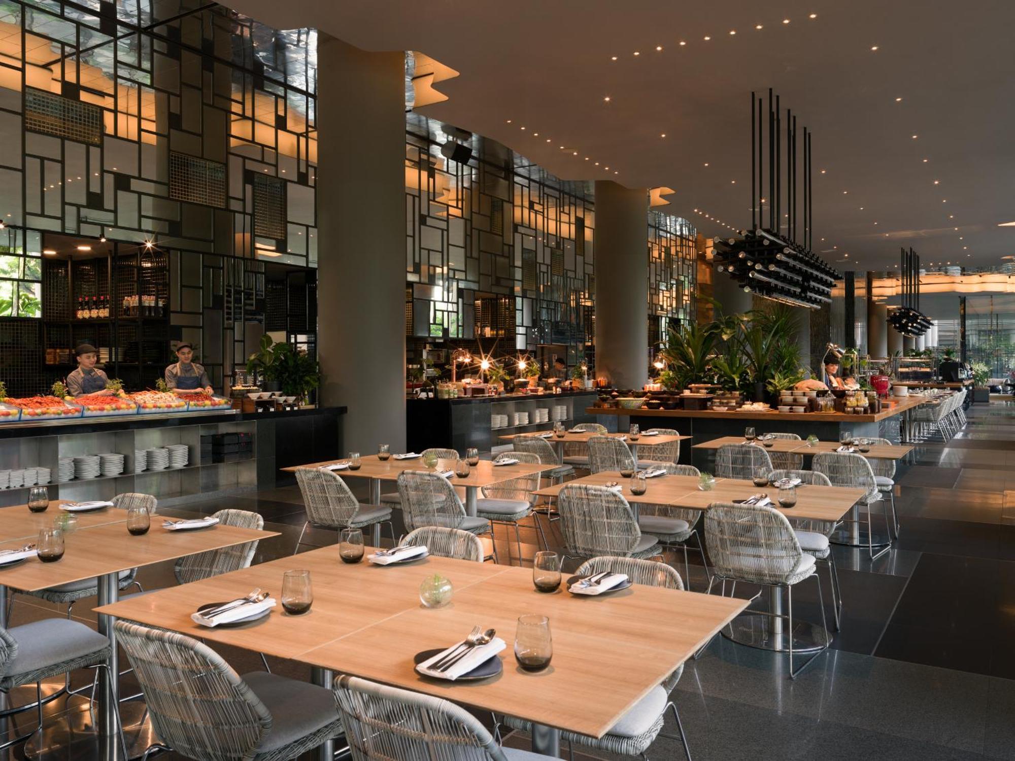 新加坡皮克林宾乐雅臻选酒店 外观 照片 The photo shows a modern restaurant interior with a spacious layout. There are several tables with wooden tops and transparent chairs arranged neatly. The design features large windows and stylish lighting, creating a warm ambiance. In the background